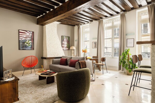 Una sala de estar moderna con chimenea, un sofá, una mesa de centro y un ventanal con cortinas.