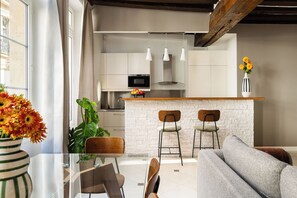 Une cuisine moderne dotée d’un îlot central, de tabourets de bar et de luminaires suspendus.