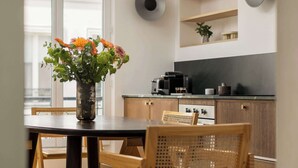 Una cocina moderna con armarios de madera, encimera negra y comedor con mesa y sillas.