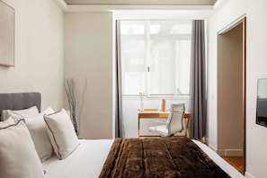 Une chambre à coucher avec un lit, un bureau, une chaise, une fenêtre et un téléviseur.