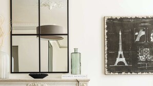 A living room with a fireplace, a sofa, a coffee table, a vase with flowers, and a framed picture of the Eiffel Tower.