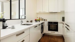 A modern kitchen with white cabinetry, a built-in washing machine, and a dishwasher.