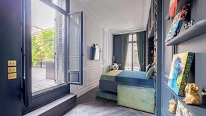 A room with a bed, a window with curtains, a shelf with decorative items, and a panda plush toy. - Stylish 4 Beds by Trocadéro (Paris)
