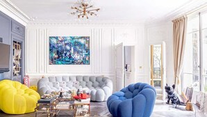 A spacious living room with a large painting, a blue armchair, a yellow bean bag, and a grey sofa. - Stylish 4 Beds by Trocadéro (Paris)