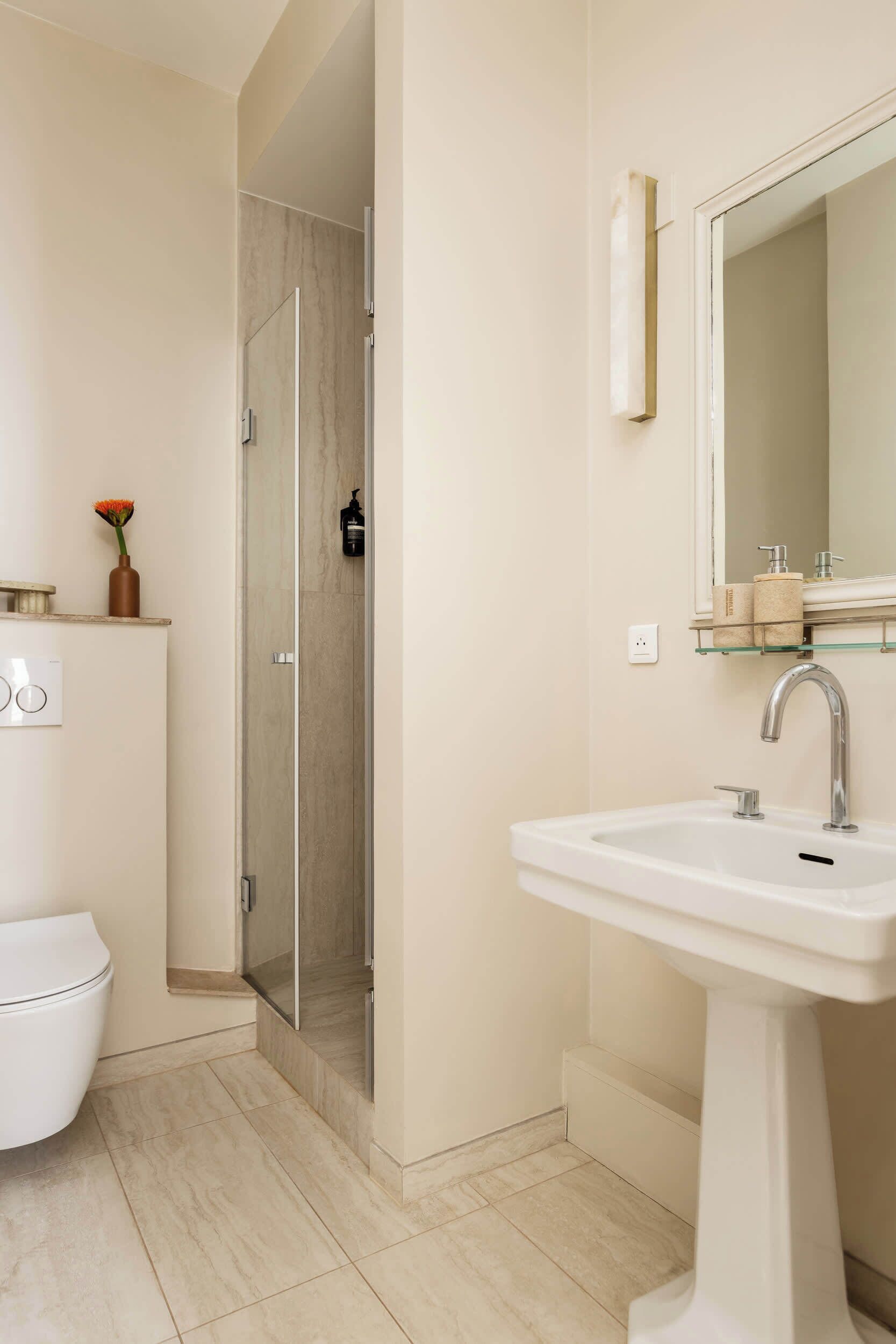 A modern bathroom with a white sink, a glass shower enclosure, and a toilet.