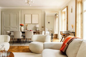 A spacious living room with a round coffee table, a sofa, and a dining area with chairs and a table.