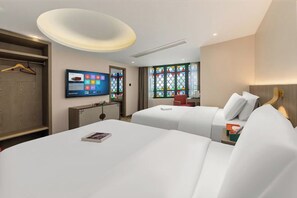 Une chambre d’hôtel avec deux lits, une télévision, un bureau et une fenêtre ornée de vitraux.