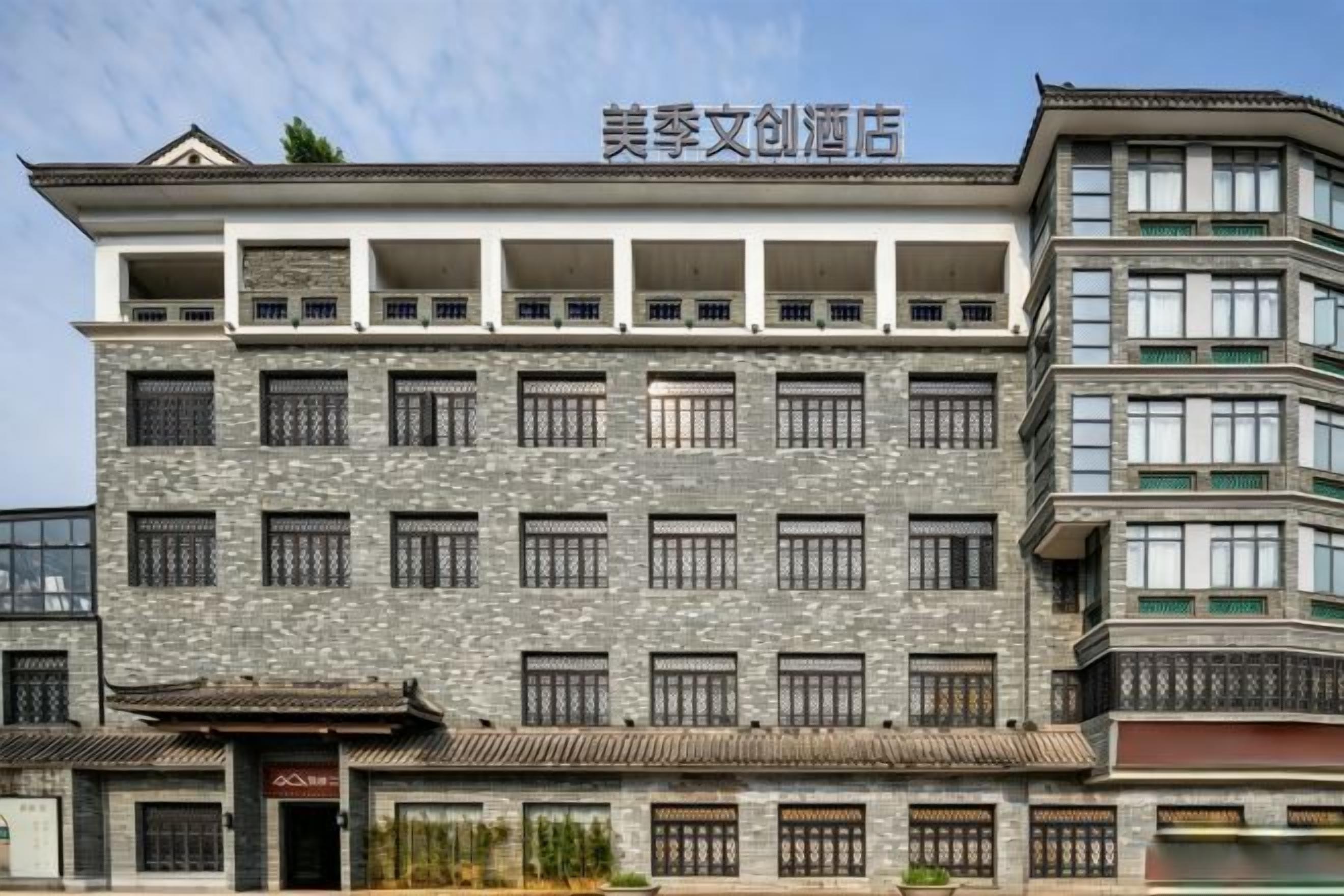 A multi-story hotel with a traditional architectural style, featuring a prominent entrance with a red sign.