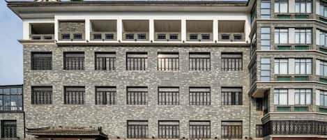A multi-story hotel with a traditional architectural style, featuring a prominent entrance with a red sign.