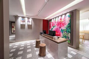Un espace d'accueil comprenant un comptoir de réception, une grande œuvre d'art florale accrochée au mur et un comptoir d'enregistrement.