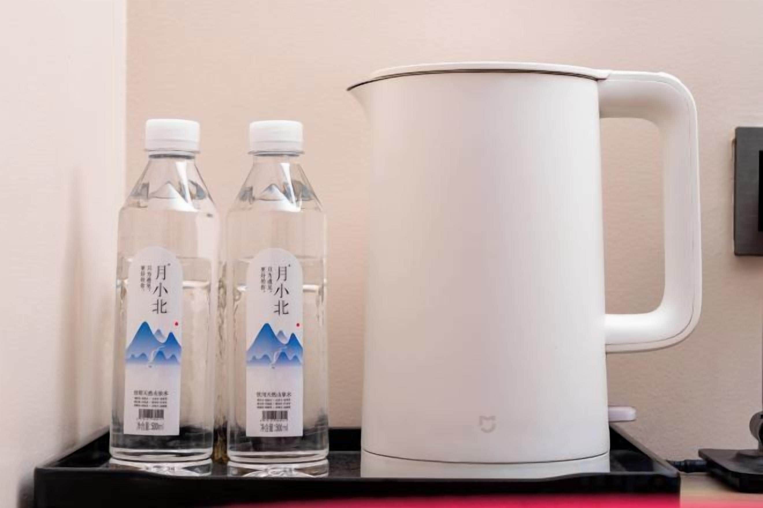 Two clear water bottles and a white electric kettle on a black tray.