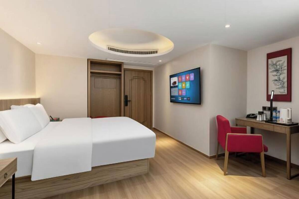 Een hotelkamer met een bed, bureau, televisie en een deur.