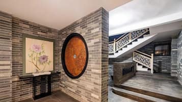 A modern interior with a stone wall, a round wooden table, and a staircase with a black railing.
