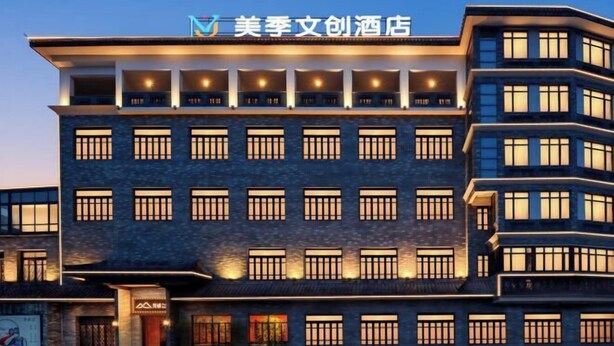 Un hotel de varios pisos con un diseño moderno, que presenta una entrada destacada y varios balcones.