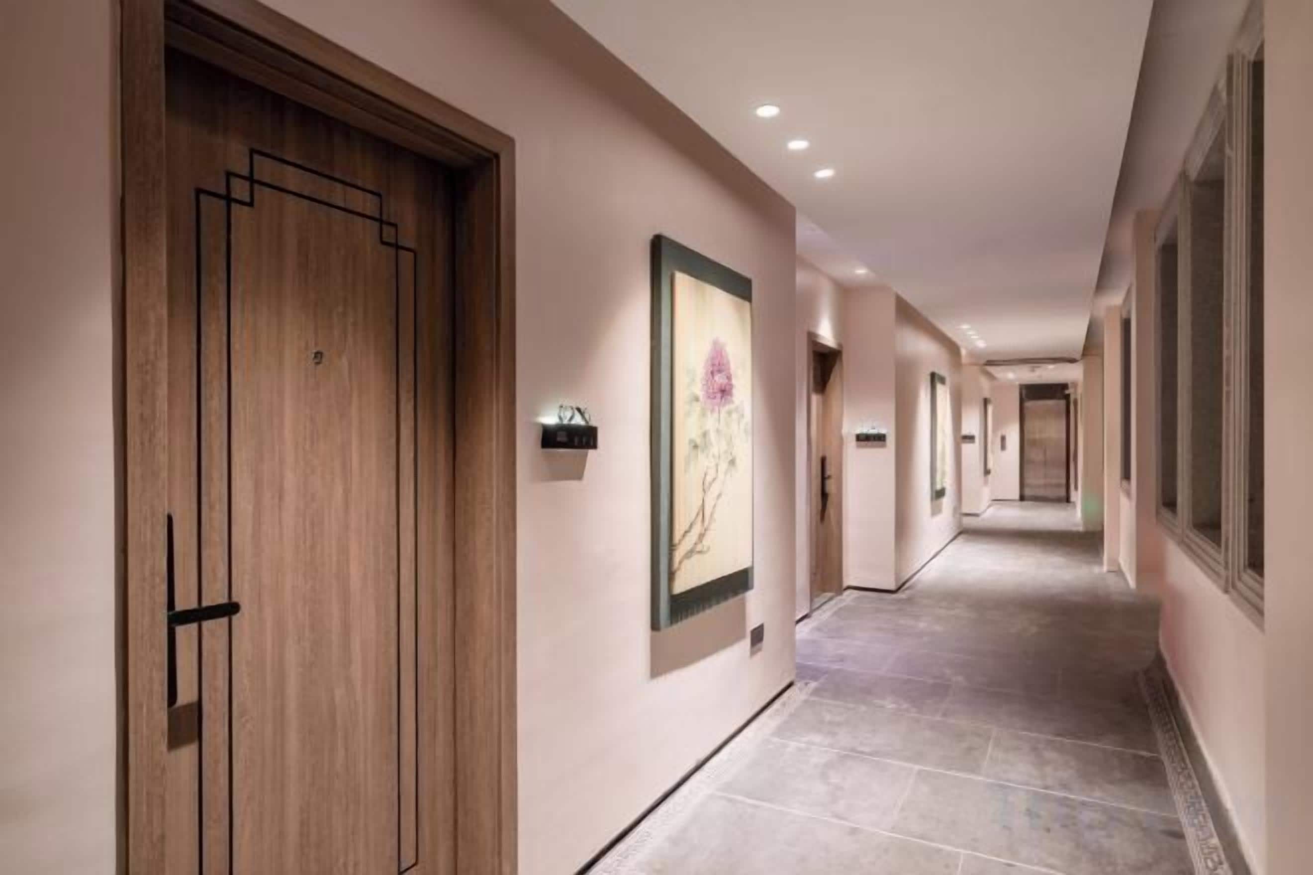 Um corredor com portas de madeira, obras de arte emolduradas e piso de azulejos.