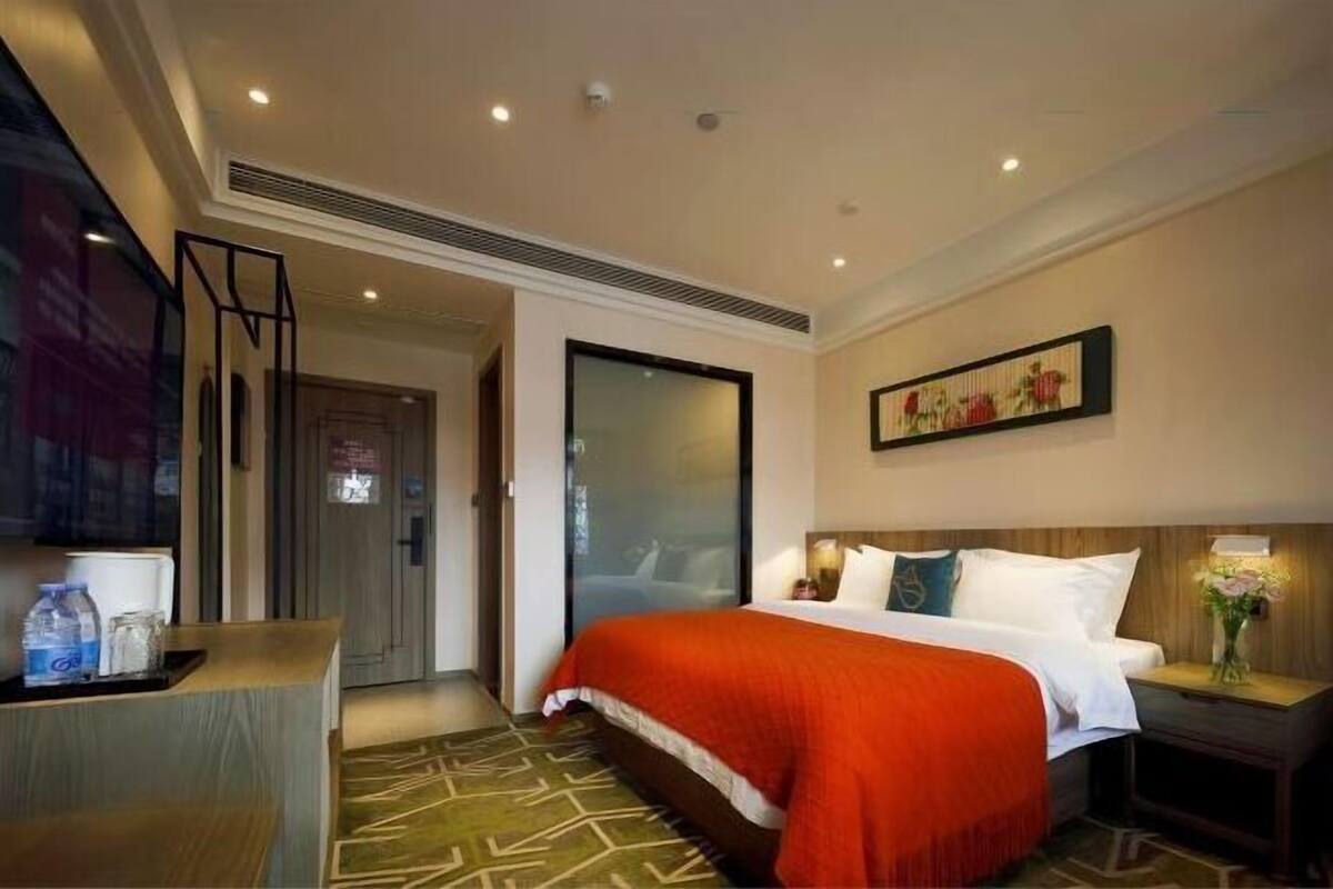 Een hotelkamer met een bed, een bureau, een stoel, een deur en een kunstwerk aan de muur.