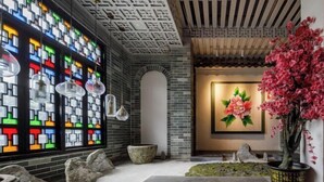 Un interior moderno con una pared de mosaicos, un banco de piedra y una planta en maceta.