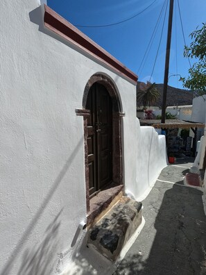 Un bâtiment blanc avec une porte marron et un petit escalier en pierre menant à l’entrée.