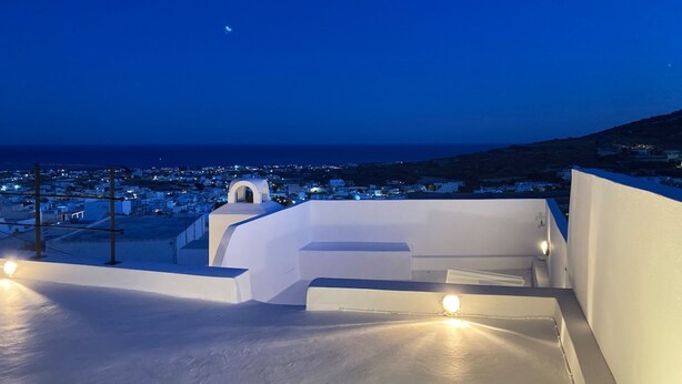 A rooftop terrace with a view of a coastal town at dusk. - The Commander s House (Santorini)