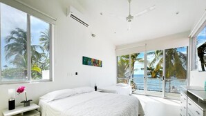 A modern bedroom with a large bed, a nightstand, and a view of the ocean. - Quinta del Mar El Francés (Tolu)