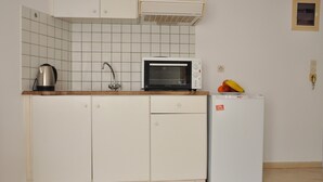 Una cocina compacta equipada con microondas, hervidor y refrigerador pequeño.