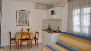 Un espacio habitable compacto con kitchenette, comedor y sofá.