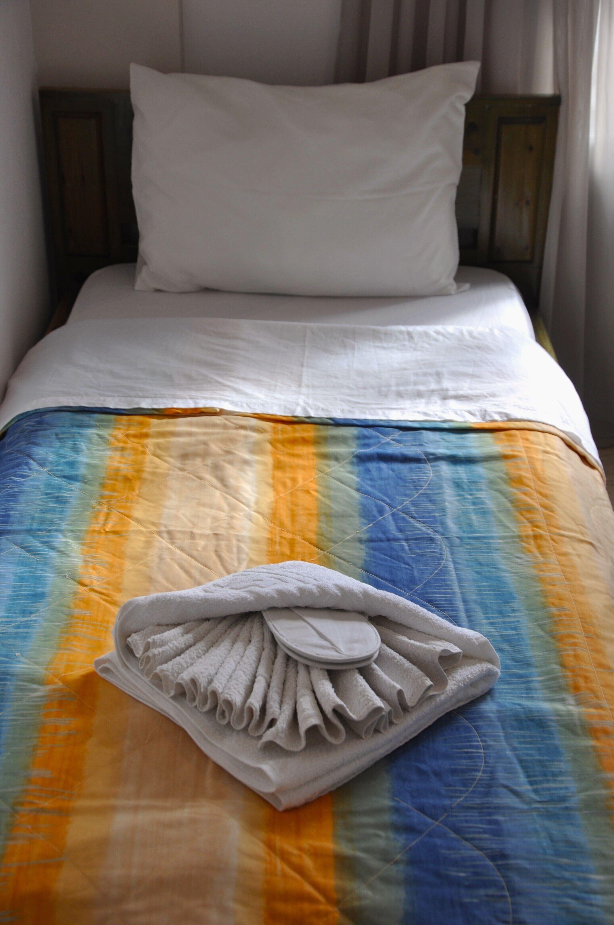 Una cama bien hecha con un edredón colorido y una toalla doblada.
