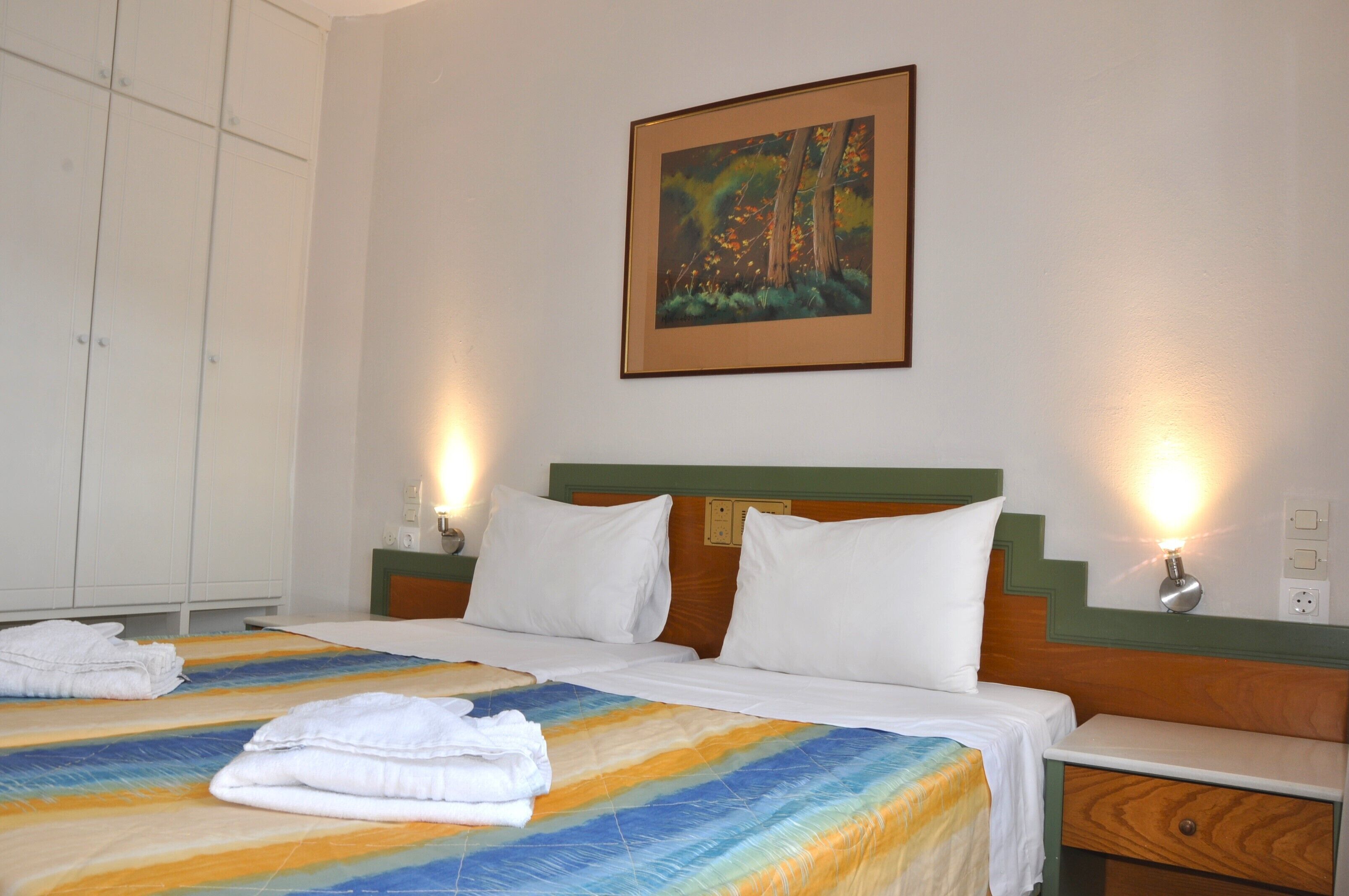 Ein Hotelzimmer mit einem Bett, zwei Nachttischen, einem Schrank und einem Gem älde an der Wand.