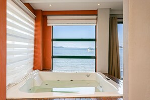 Ein modernes Badezimmer mit einer großen Badewanne, Meerblick und einer Schiebetür.