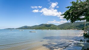 Une plage avec des bateaux, une promenade en bois et des montagnes en arrière-plan.