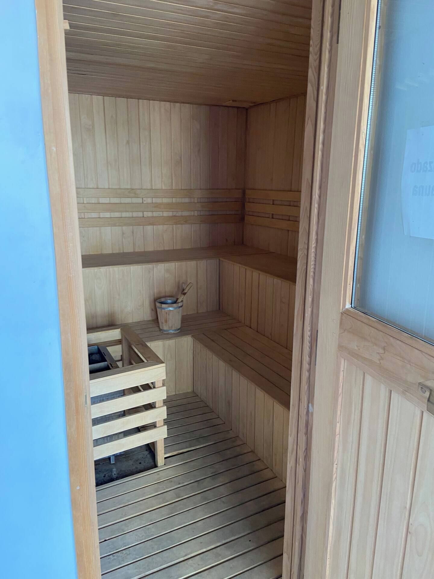 A sauna room with wooden benches and a bucket.