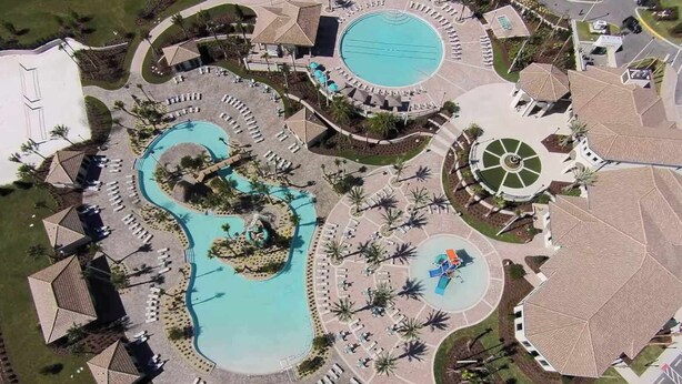 An aerial view of a resort with multiple swimming pools, sun loungers, and palm trees.