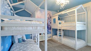 A room with bunk beds, a chandelier, and a mountain-themed wall mural.