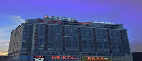 Um hotel com vários andares e placas indicando KTV e outras comodidades.