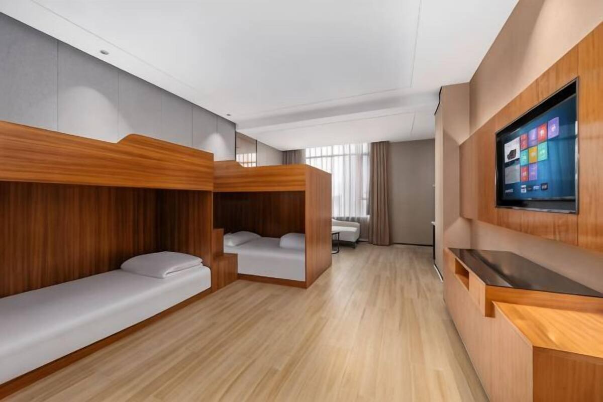 Una habitación de hotel moderna con literas, un televisor de pantalla plana y un mostrador de recepción de madera.