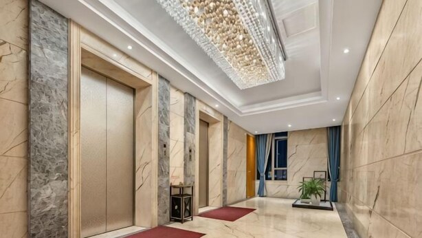 Un moderno vestíbulo de hotel con suelo de mármol, una gran araña y una planta en maceta.