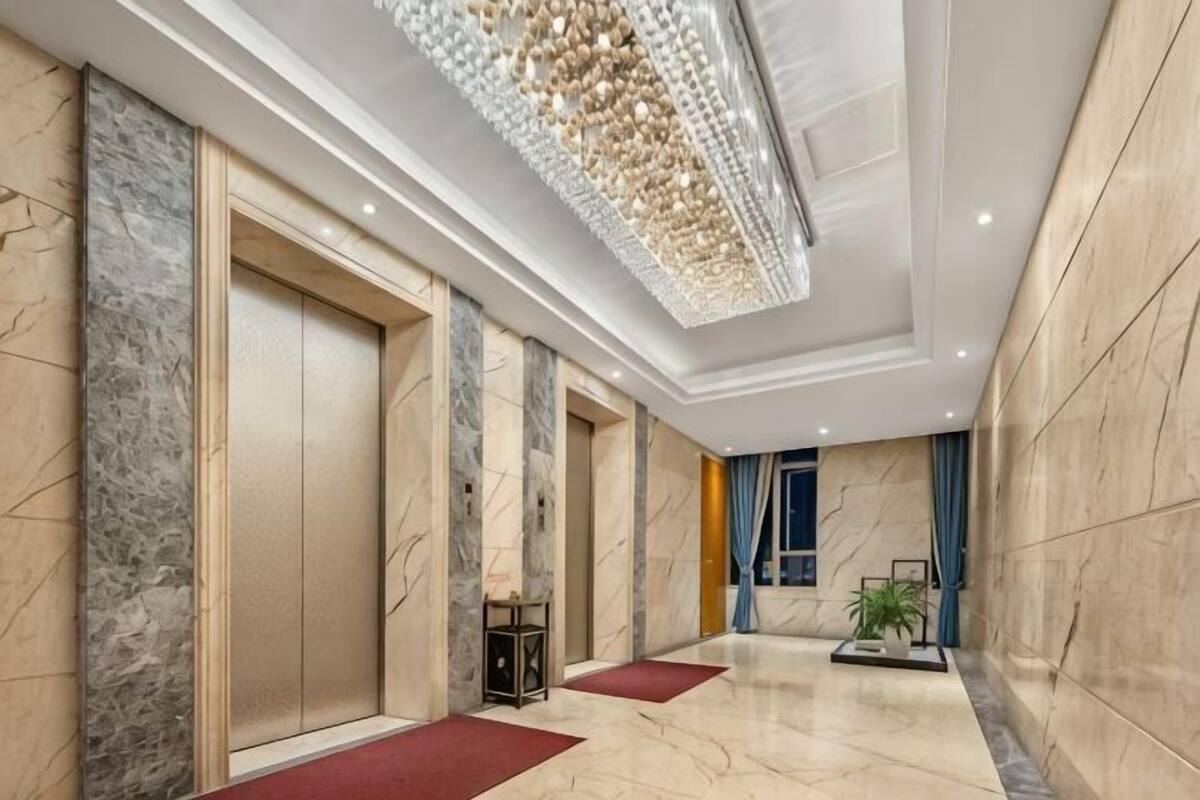 Un moderno vestíbulo de hotel con suelo de mármol, una gran araña y una planta en maceta.