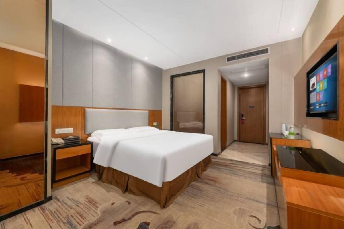 Habitación de hotel con cama, escritorio, televisor y puerta al baño.