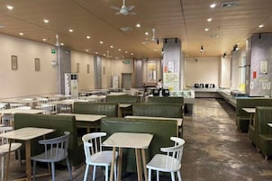 Un amplio comedor interior con varias mesas y cabinas, ventiladores de techo y un diseño moderno y cuidado.