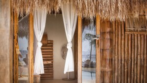 A room with a thatched roof, wooden walls, and a large mirror. - The Beach House Ocam Ocam (Busuanga)