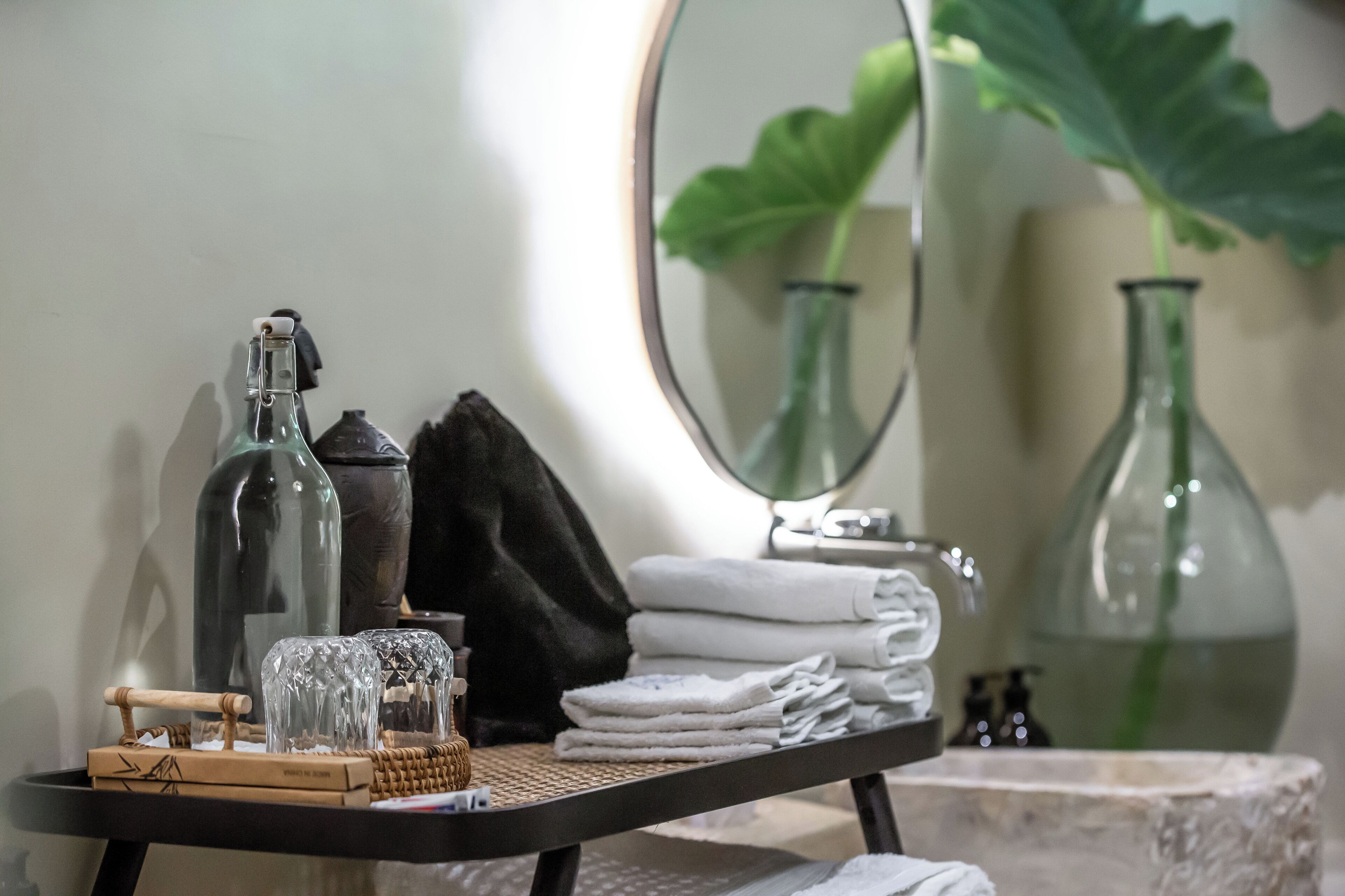 Un meuble-lavabo pour la salle de bain, avec un miroir, un porte-serviettes et une petite table où sont posés les articles de toilette.