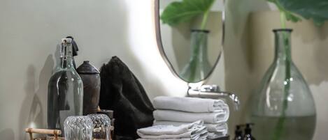 Un meuble-lavabo pour la salle de bain, avec un miroir, un porte-serviettes et une petite table où sont posés les articles de toilette.