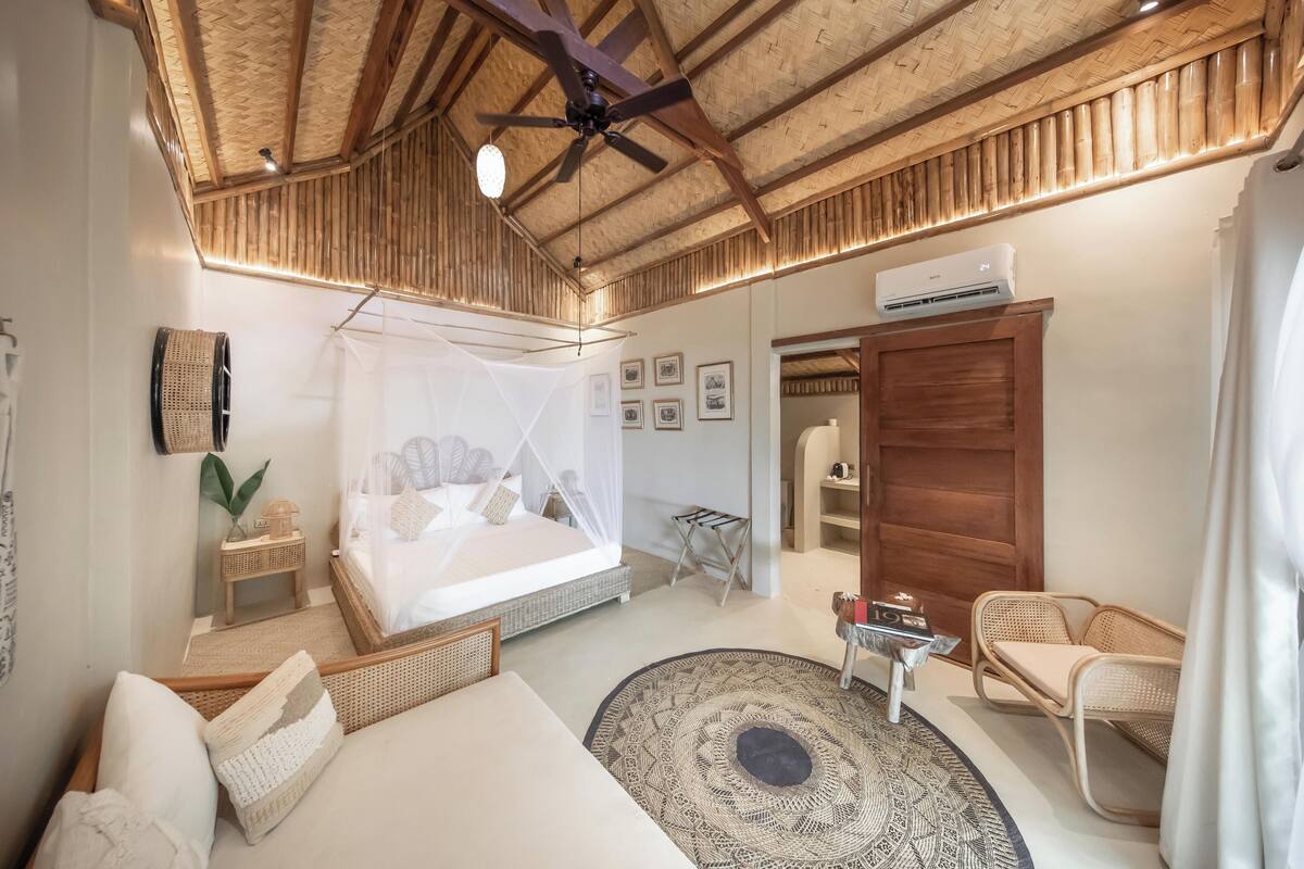 A bedroom with a bed, a ceiling fan, a bedside table, a chair, and a round rug.