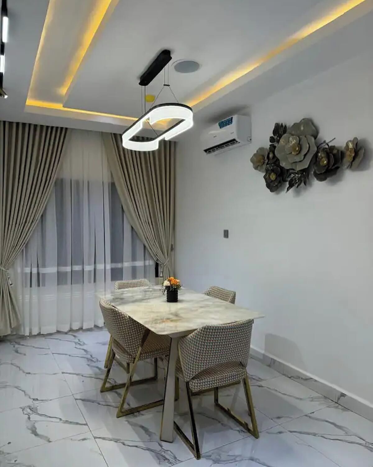 A modern dining room with a marble floor, a round table, and four chairs.