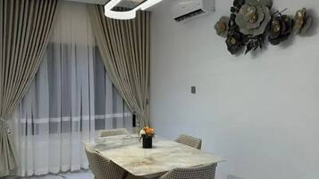 A modern dining room with a marble floor, a round table, and four chairs.