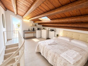 Un dormitorio con cama, escritorio, cómoda, microondas y perchero.