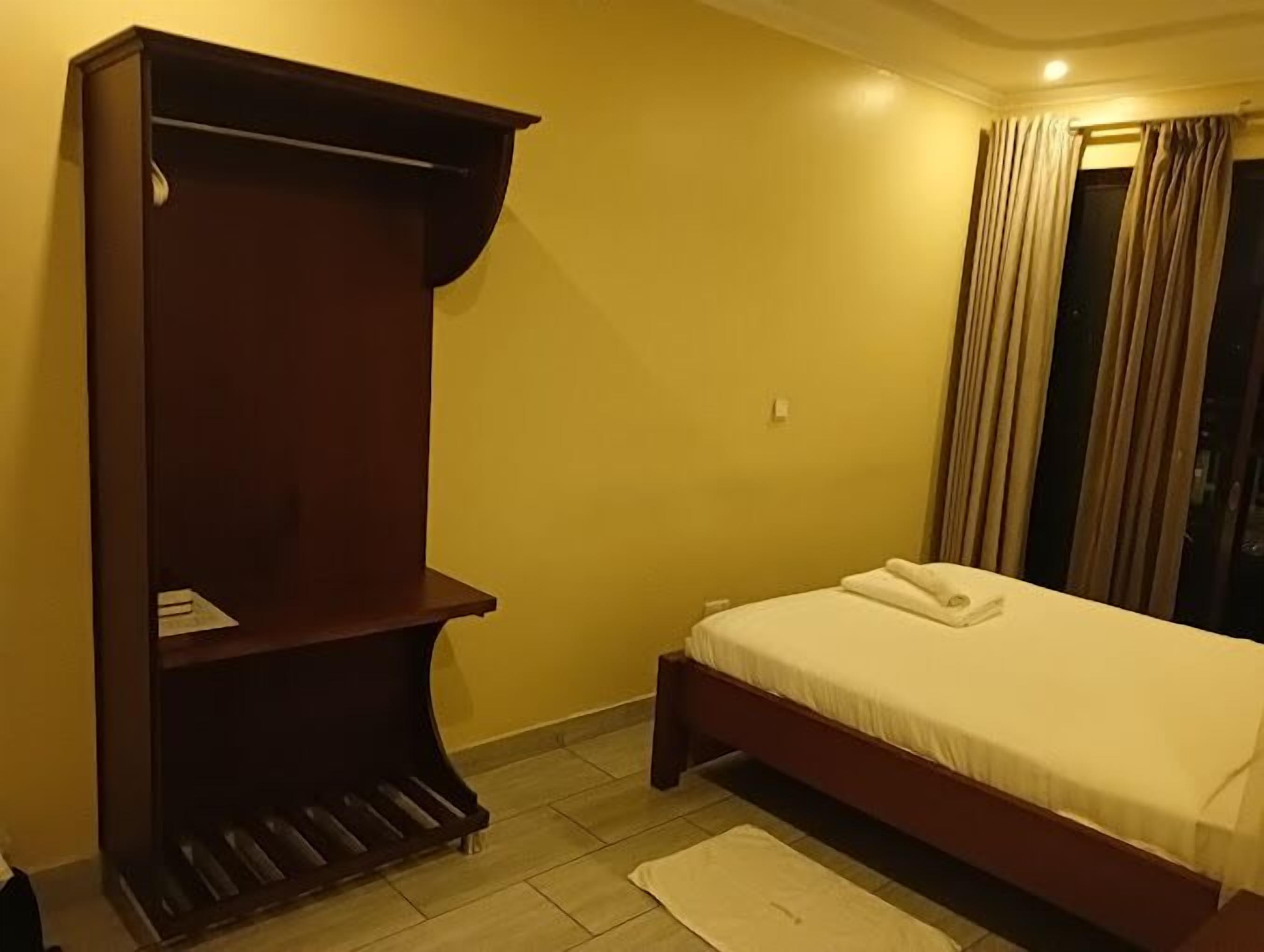Un dormitorio con una cama, un armario de madera y una ventana con cortinas.