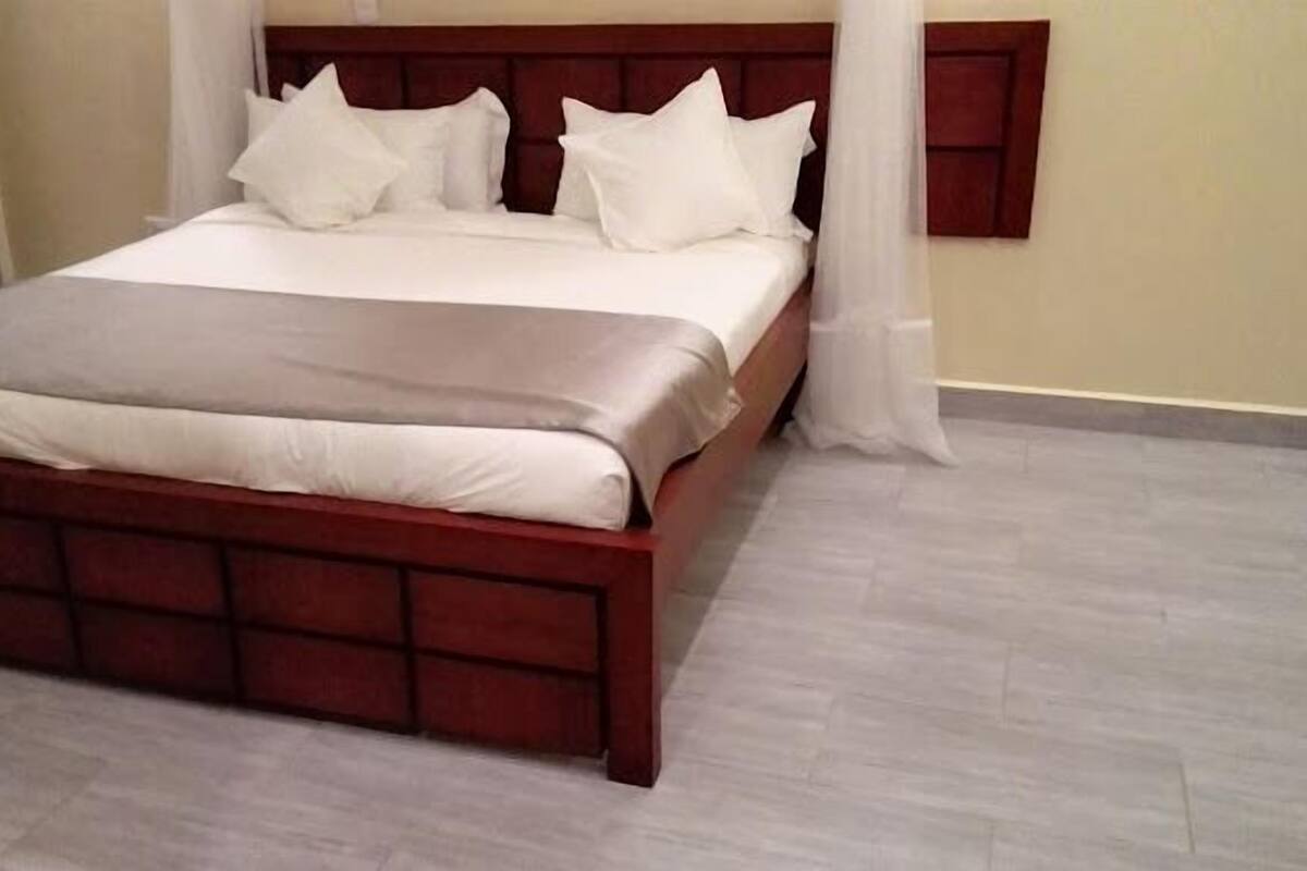 A neatly made bed with a wooden headboard, white bedding, and a grey throw blanket.