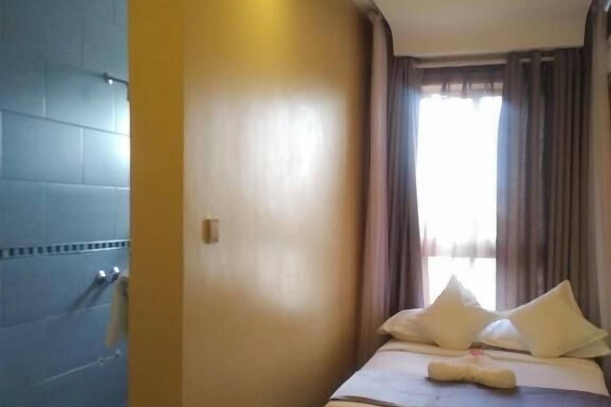 A hotel room with a bed, a shower area, and a view of the outdoors.