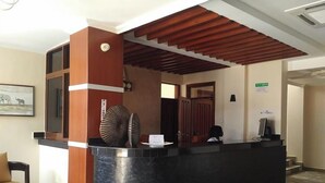 A reception desk with a black countertop, wooden accents, and a patterned floor. - Rockwell Hotel (Kisumu)
